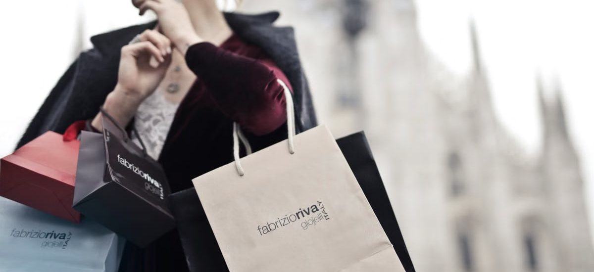 Stylish woman holding designer shopping bags near Milan's iconic Duomo. Urban fashion and lifestyle concept.