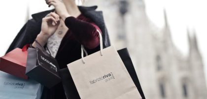 Stylish woman holding designer shopping bags near Milan's iconic Duomo. Urban fashion and lifestyle concept.