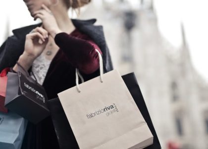 Stylish woman holding designer shopping bags near Milan's iconic Duomo. Urban fashion and lifestyle concept.