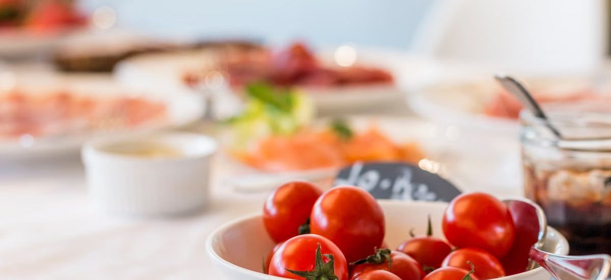 Close-up shot of vibrant cherry tomatoes in a bowl on a well-set dining table.