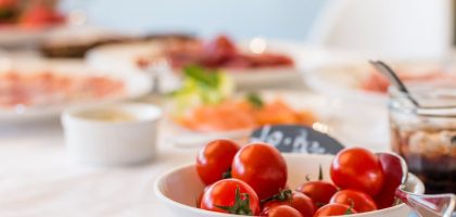 Close-up shot of vibrant cherry tomatoes in a bowl on a well-set dining table.