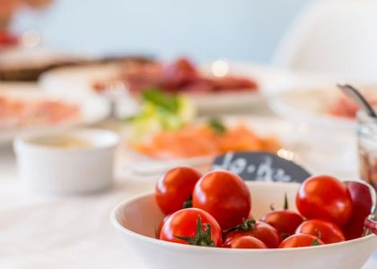 Close-up shot of vibrant cherry tomatoes in a bowl on a well-set dining table.